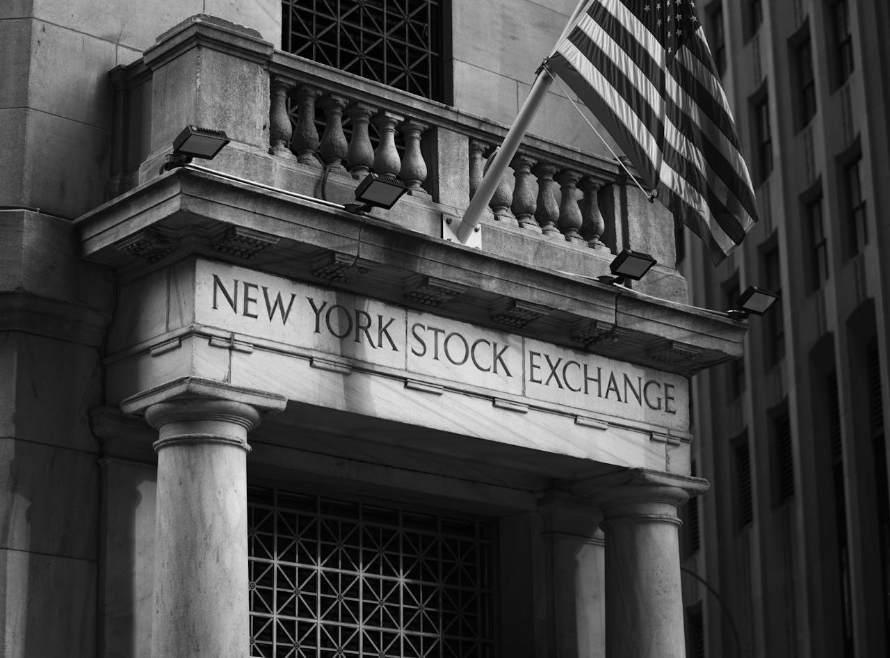 Services Black and white photo of the New York Stock Exchange facade with USA flag.