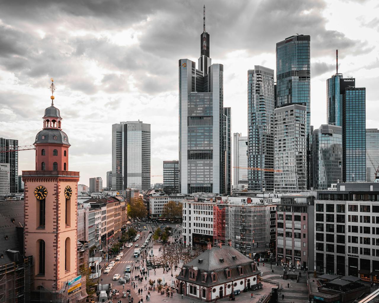 Services A stunning view of Frankfurt's skyscrapers and historical church under a cloudy sky.